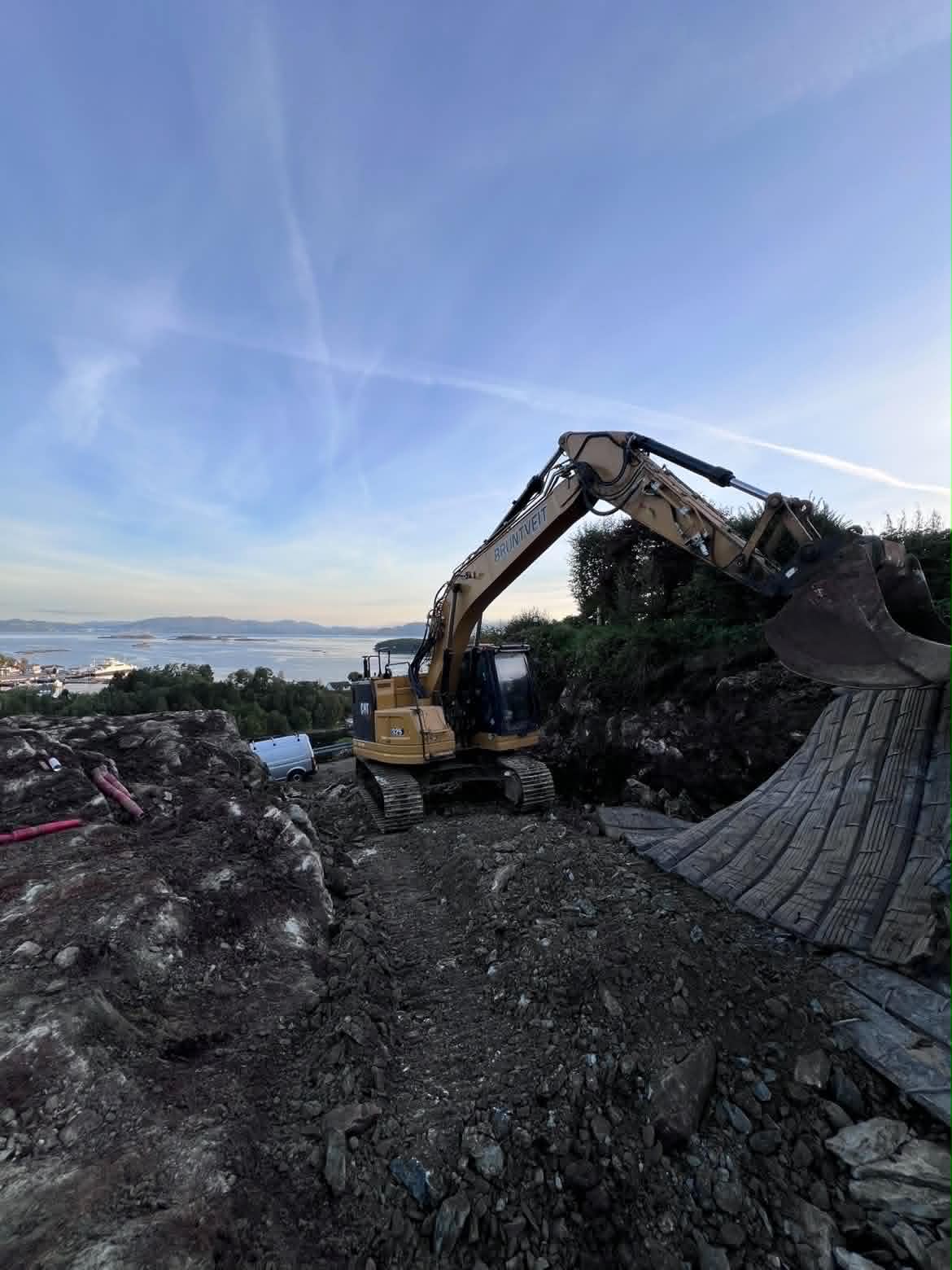 Bruntveit Maskin gravemaskin med sprengmatter og fjordutsikt
